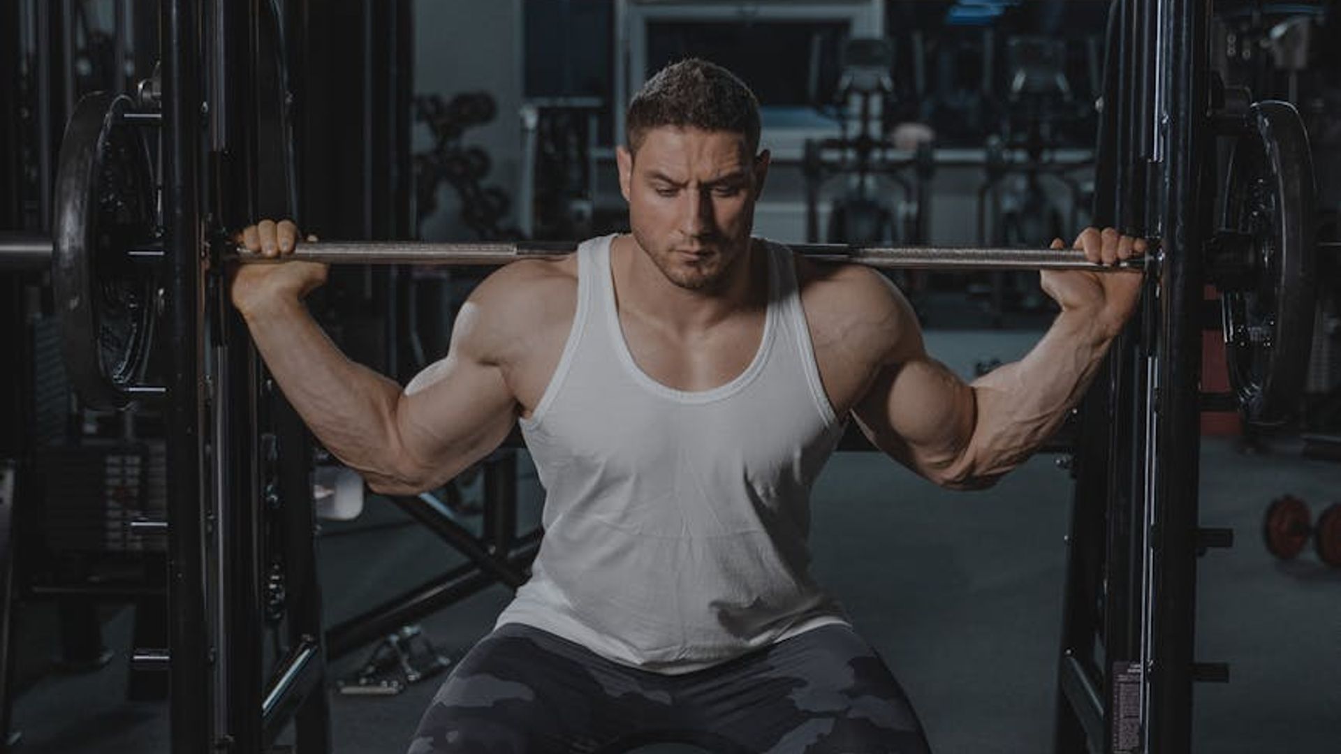 Muscular man performing strength exercises in a dark gym environment
